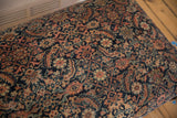 Textured antique Fereghan rug fragment showcasing intricate navy, rust, and ivory floral patterns.