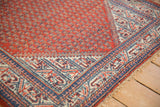 Hand-knotted Serbend rug corner with cherry red boteh field, ivory, and sapphire blue pawn motif.