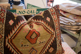 Textured hand-knotted vintage rug fragment pillow featuring tribal patterns in brown, red, and beige.