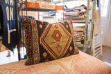 Hand-knotted tribal geometric pattern in red, cream, and dark brown on vintage rug pillow side.