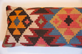Stepped geometric motifs in orange, red, blue, and brown on a vintage Kilim pillow.