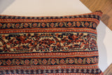 Vintage Persian rug fragment pillow detail, showcasing hand-knotted patterns in rich navy, terracotta, and light beige.