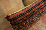 Vintage Persian rug fragment pillow with navy, rust, and teal hand-knotted patterned edge.