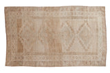 Distressed Kars carpet, geometric diamond medallions, abrashes field, muted beige tones, 6' x 9'11