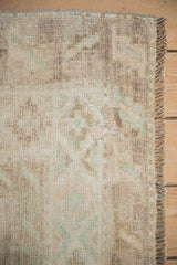 Distressed short pile texture and fringe of a vintage Kars rug in sand and seafoam tones.