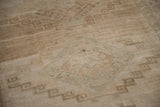 Distressed short pile Kars carpet with muted sand and beige, revealing faint stylized geometric patterns.