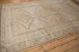 Distressed Kars carpet corner, showing secured end, geometric border, and abrashed pale coffee.