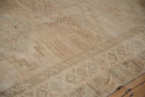 Distressed texture and faded geometric motifs on a Kars carpet in soft beige and pale green.
