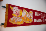 Close-up of vintage circus felt pennant showing aged brown binding and clown graphic.