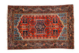 Vintage Persian Tajabad rug with a navy geometric medallion, rust red field, and sapphire blue corners.
