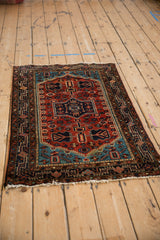 Angled view of a vintage Tajabad rug showing its rust-red field, navy blue medallion, and intricate borders.