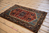Angled perspective view of a vintage Tajabad rug with its rust field and geometric navy blue medallion.