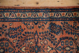 Terracotta field with sapphire blue Sarouk stylized floral sprays and patterned border.