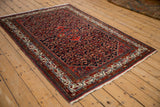Angled perspective of a vintage Persian Hamadan rug with a navy blue Herati-patterned field.
