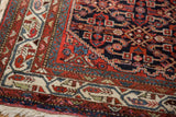 Detailed corner of a hand-knotted Hamadan rug with geometric ivory, red, and dusty teal borders.