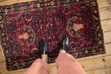 Overhead view of a vintage Lilihan rug, showing its scale with a red and navy floral design.
