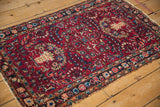 Angled view of a vintage Persian Lilihan rug with a red field and sapphire blue floral sprays.