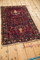Vintage Lilihan rug with a cherry red floral pattern and navy border, shown from a high angle.