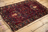 Angled view of a vintage Lilihan rug, highlighting the tattered sides and navy floral border.