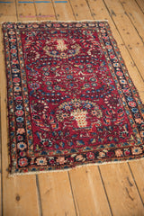 Angled perspective of a vintage Lilihan rug, highlighting its red floral field and tattered edges.