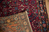 A vintage Lilihan rug's corner folded back to reveal its hand-knotted foundation and red pile.