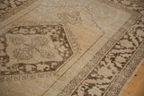Vintage distressed Oushak rug with coffee brown stepped spandrel and ivory abrashed field.