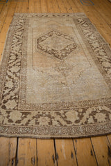 Distressed vintage Oushak rug corner with ornate brown border and exposed foundation.
