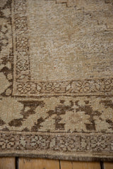 Distressed Oushak carpet showing heavy wear, visible foundation, and muted brown-ivory tones.