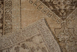 Distressed Oushak carpet close-up, showing brown tones, exposed ivory foundation, and secured side selvedge.