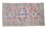 Decorative vintage Oushak rug with faded rose and navy floral motifs on an abrashed field.