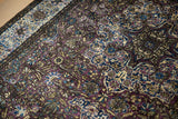 A close view of the original purple silk selvage and floral field of an antique Kashan rug.