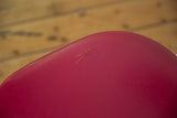 A minor surface impression on the curved, aged red vinyl upholstery of the swivel chair.