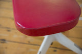 Underside of Vintage Okamura swivel chair seat, showing dark pink vinyl and exposed foam.