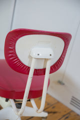 Aged red vinyl backrest and chipped ivory metal support bars on the vintage Okamura chair.