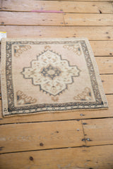 Angled perspective of a distressed Oushak mat with a dusty rose medallion and worn texture.