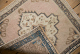 Folded corner of a vintage Turkish Oushak rug reveals the hand-knotted back with dusty teal blue accents.