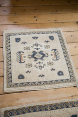 Corner of distressed Oushak rug, with dusty navy wave border and ivory field patterns.