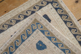 Distressed vintage Oushak rug with visible machine-bound edge and dusty navy wave border.