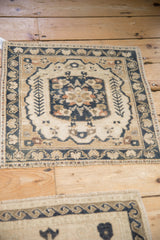 Distressed Oushak rug central floral medallion, v-shaped stems in dusty navy, cream, sand.