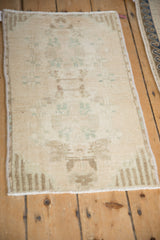 Distressed vintage Oushak rug mat: faded cream and sea foam green floral motifs, machine-bound edge.