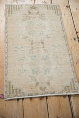 Vintage distressed Oushak rug mat with muted cream, pale green tones, and uniform wear.