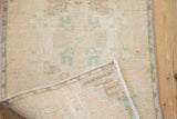 Curled corner of a distressed vintage Oushak rug, highlighting pile texture and machine-bound edge.