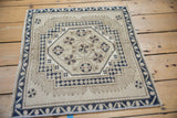 Corner detail of distressed Oushak rug with cream, navy blue meandering vine border.