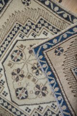 Distressed vintage Oushak rug with cream field, stylized motifs, and dusty navy border.