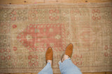 Distressed vintage Oushak rug showcasing faded pink, blush, and sage geometric patterns with visible foundation.
