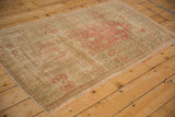 Distressed Oushak rug, close-up of worn pink, sage, and ivory geometric patterns with visible foundation.