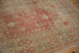 Distressed vintage Oushak rug showing worn pink, ivory pile and geometric star motifs.