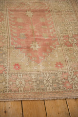 Vintage distressed Oushak rug showing worn fringe, low pile, and geometric blush-pink border.