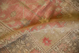 Storied texture and exposed foundation of a distressed Oushak rug in faded blush and ivory.