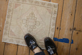 Distressed vintage Oushak mat with faded cream, dusty rose floral medallion.